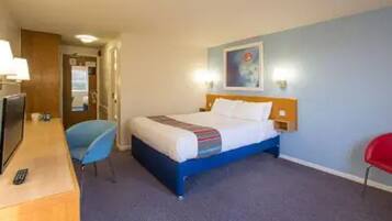 A hotel room with a bed, a desk, a chair, and a television.