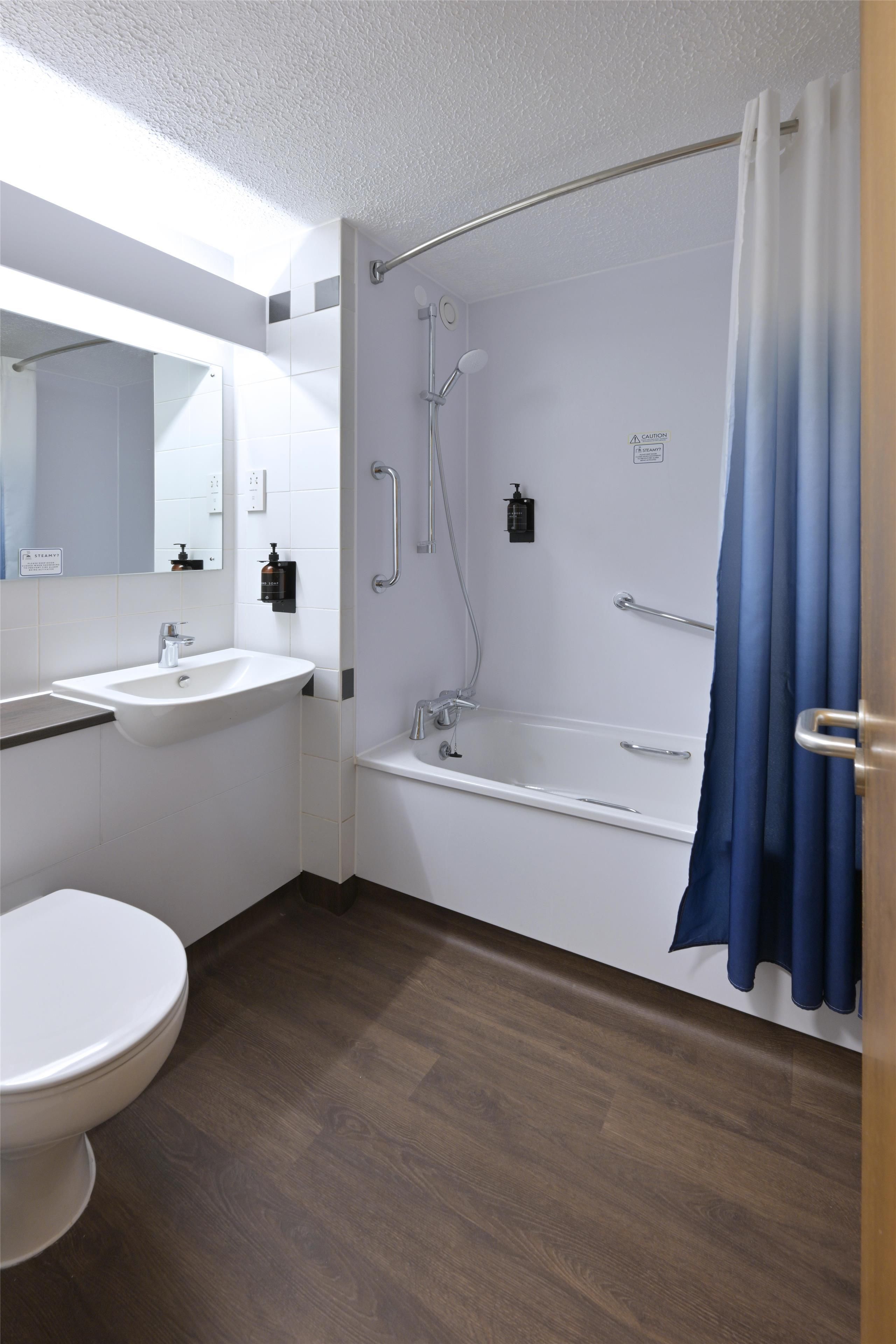 A modern bathroom with a bathtub, shower, sink, and toilet.