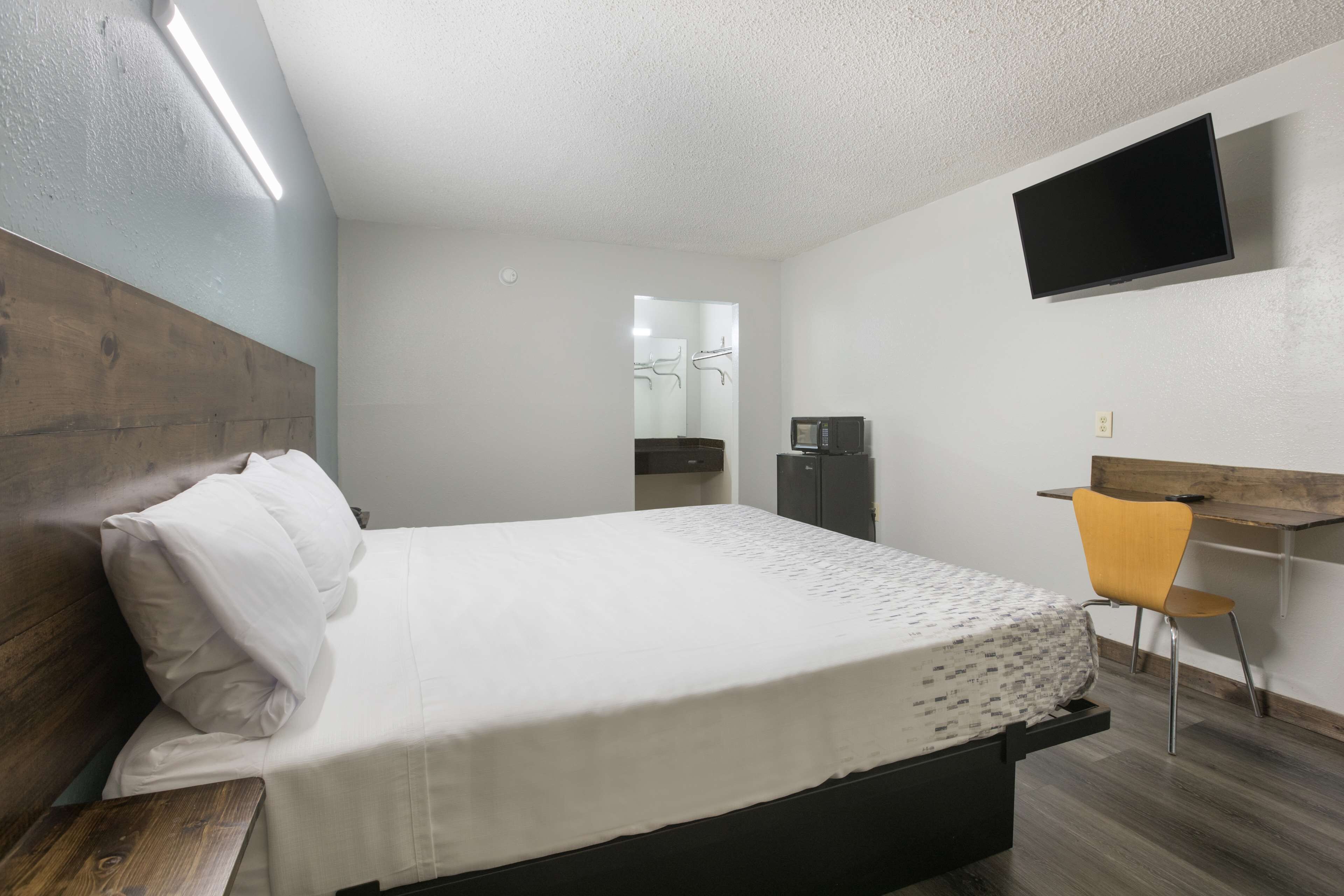Une chambre à coucher avec un lit, un bureau, une chaise, une télévision et un miroir.