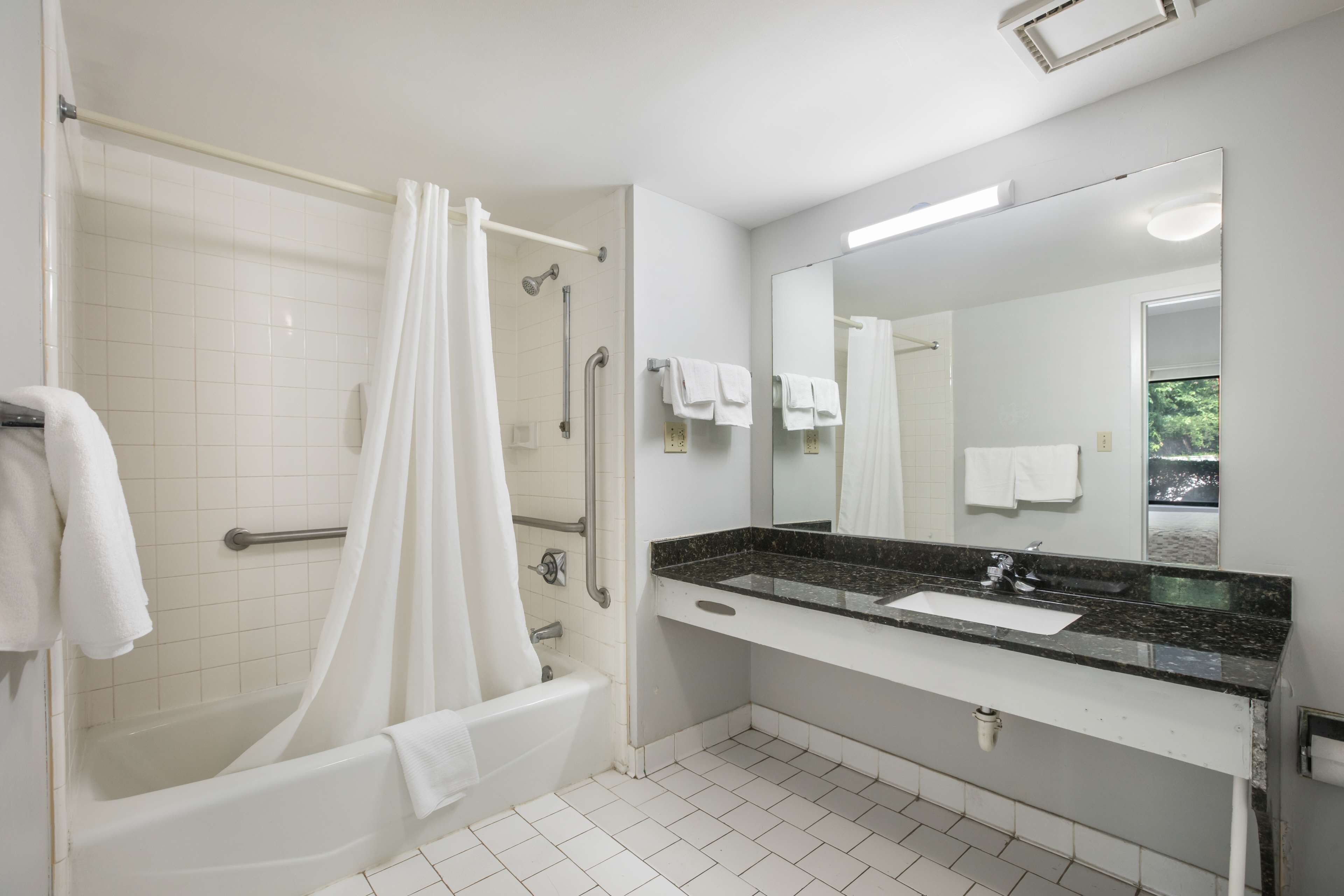 A bathroom with a bathtub, shower, and sink.