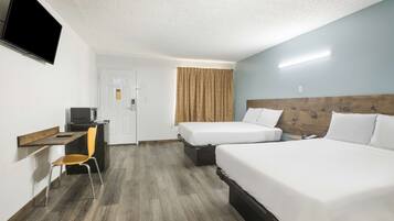 A hotel room with two beds, a desk with a chair, a television, and a door.