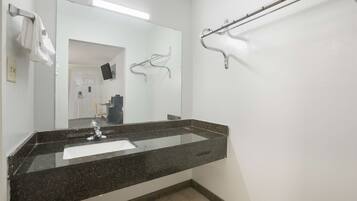 A bathroom with a granite countertop sink, a mirror, a towel rack, and a grab bar.