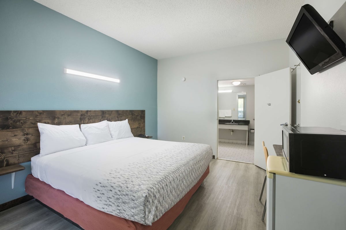 A hotel room with a bed, a television, and a kitchenette.