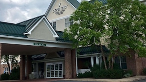 A Country Courtyard Inn & Suites building with a covered entrance, brick facade, and a green roof. - Country Inn & Suites by Radisson, Lewisburg, PA (Lewisburg)