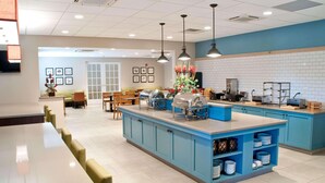 A modern kitchen area with blue cabinets, a central island with a sink, and overhead lighting. - Country Inn & Suites by Radisson, Lewisburg, PA (Lewisburg)