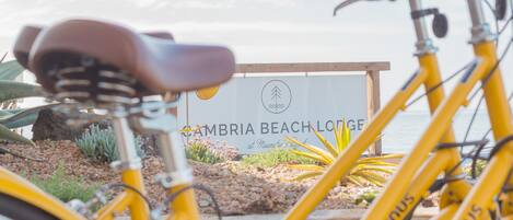 A yellow bicycle in front of a sign for Cambria Beach Lodge.