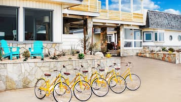Un edificio moderno con fachada de piedra, una terraza de madera y una fila de bicicletas amarillas estacionadas al frente.