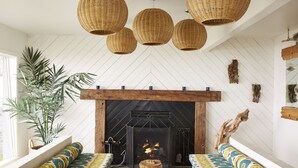 A cozy living room with a fireplace, wicker pendant lights, and patterned sofas. - Cambria Beach Lodge (Cambria)