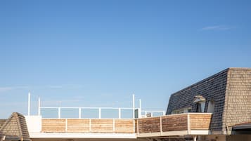 A waterfront property with a wooden deck, a balcony, and a view of the water.