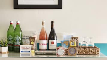 A shelf with various items including bottles of water, a bottle of wine, a book, and some toiletries.