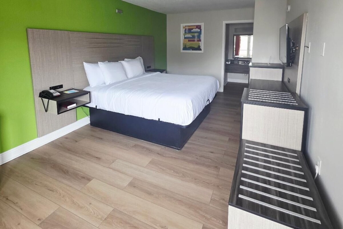 A hotel room with a bed, bedside table, and a TV stand.