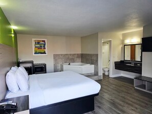 A hotel room with a bed, a bathroom with a bathtub, a toilet, and a sink.