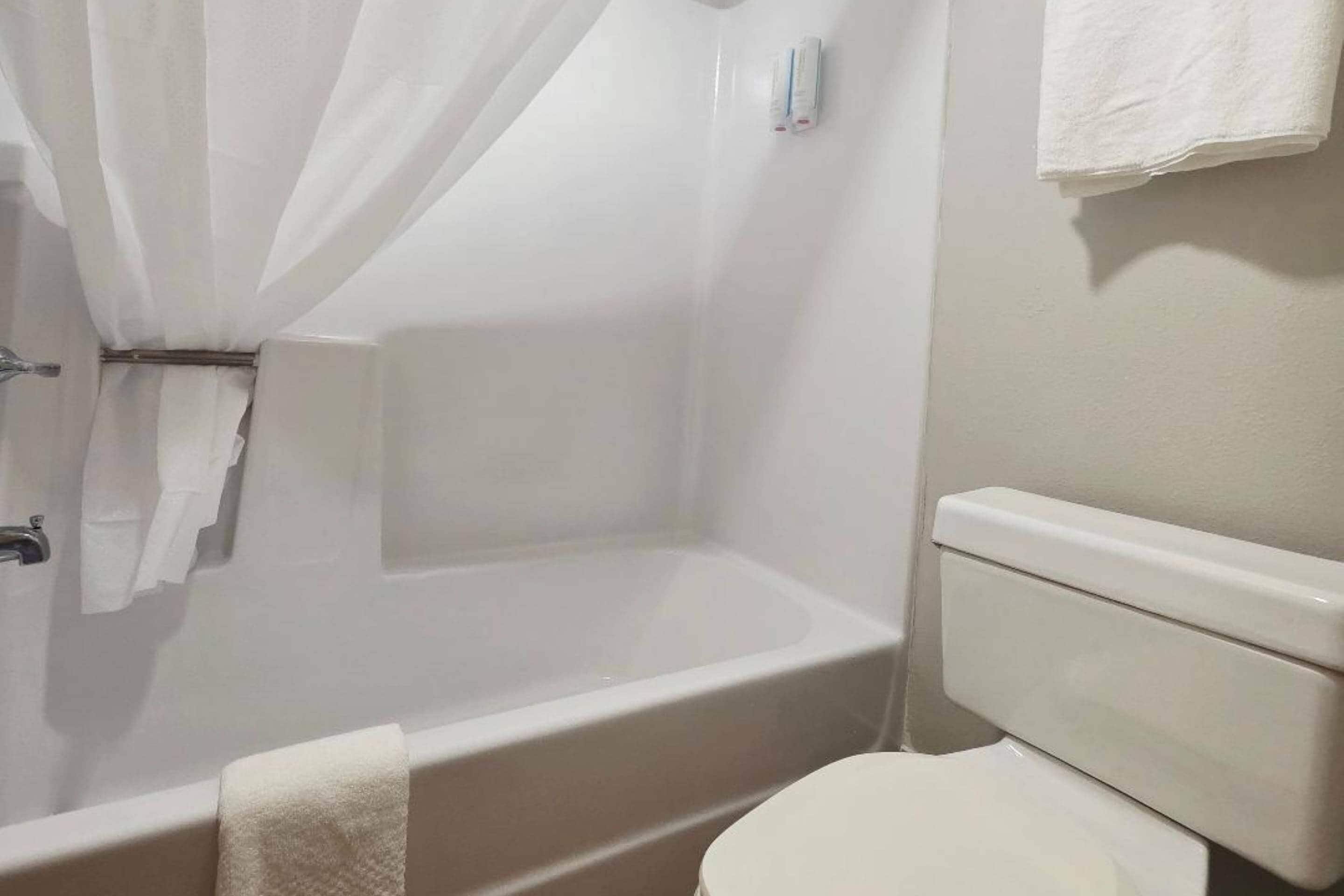 Un baño con bañera, inodoro y cortina de ducha.