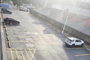 A parking lot with marked handicapped spaces, a white SUV, and a building with red windows in the background.