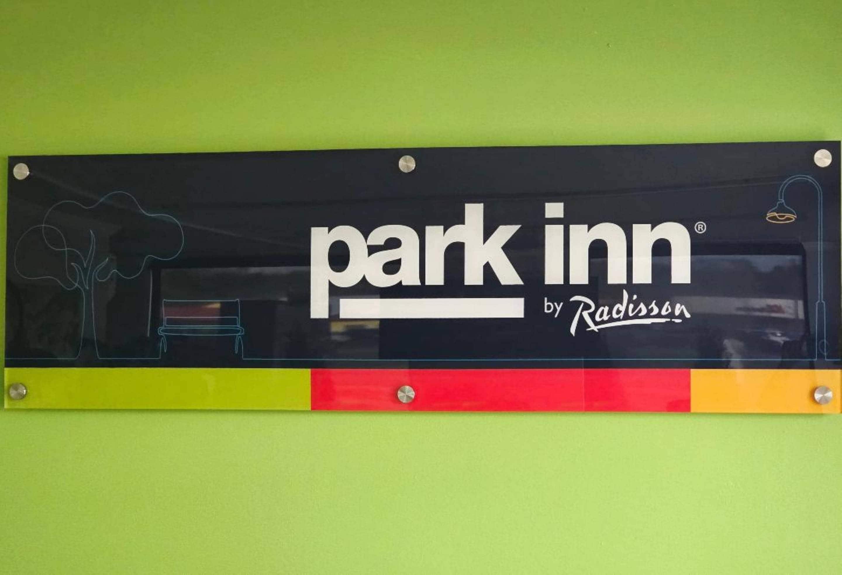 Señal del Park Inn by Radisson con un diseño sencillo e ilustración de un árbol.