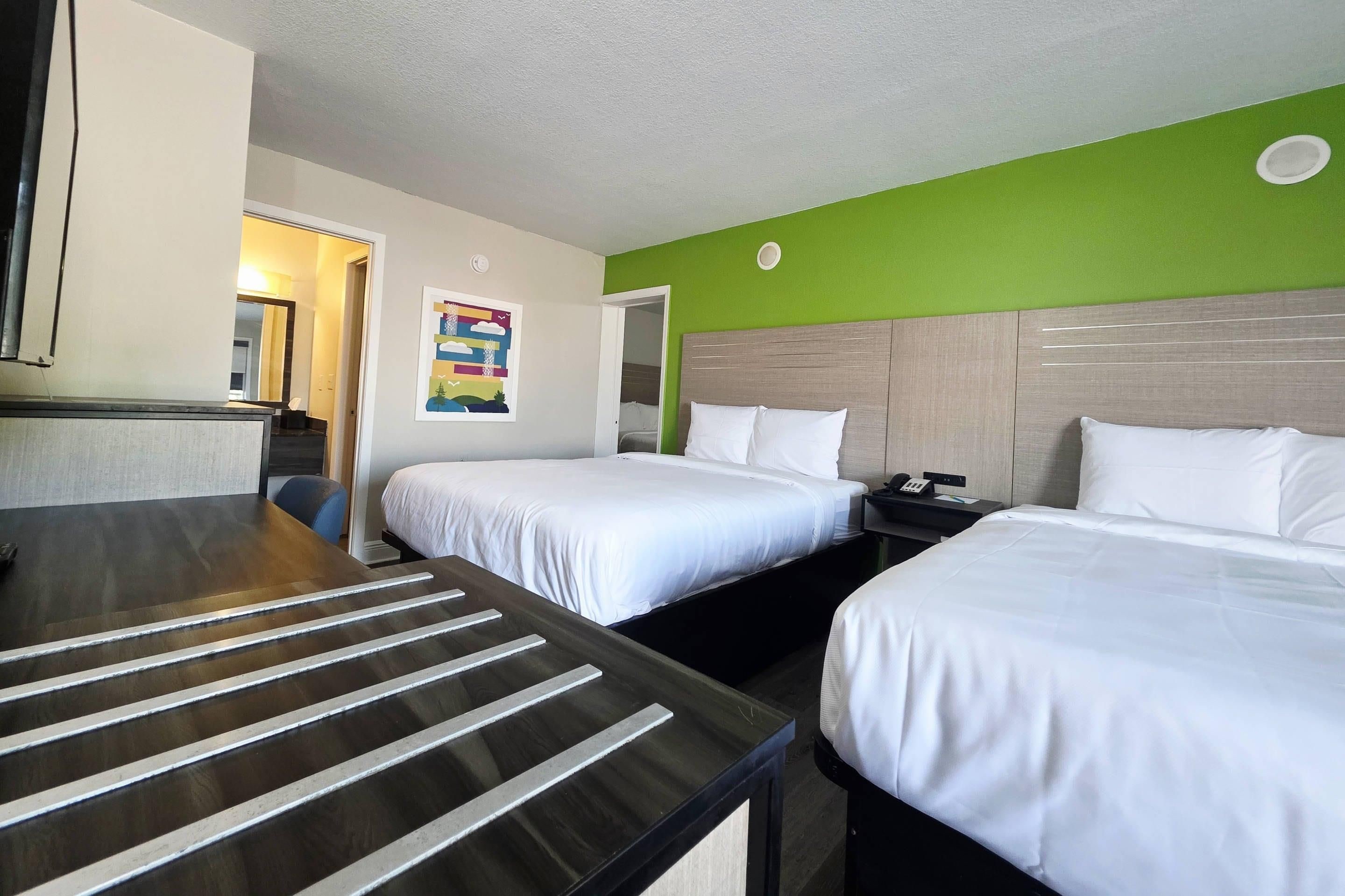Una habitación de hotel con dos camas, un escritorio y un baño.