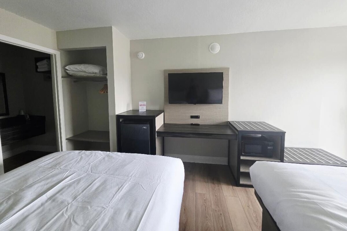 A hotel room with two beds, a desk, a television, and a wardrobe.