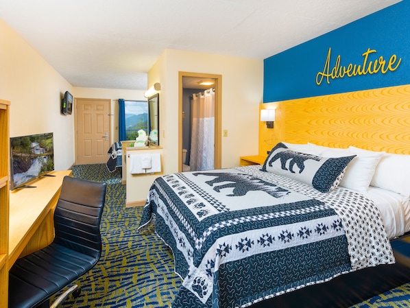 A hotel room with a bed, a desk, a chair, and a television.