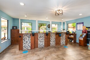 A reception area with a counter, a clock, and a sign promoting good health.