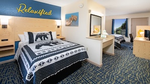 A hotel room with a bed, a desk, a mirror, and a window.