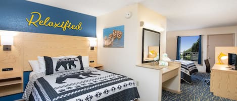 Una habitación de hotel con una cama, un escritorio, un espejo y una ventana.