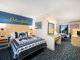 A hotel room with a bed, a desk, a mirror, and a window.