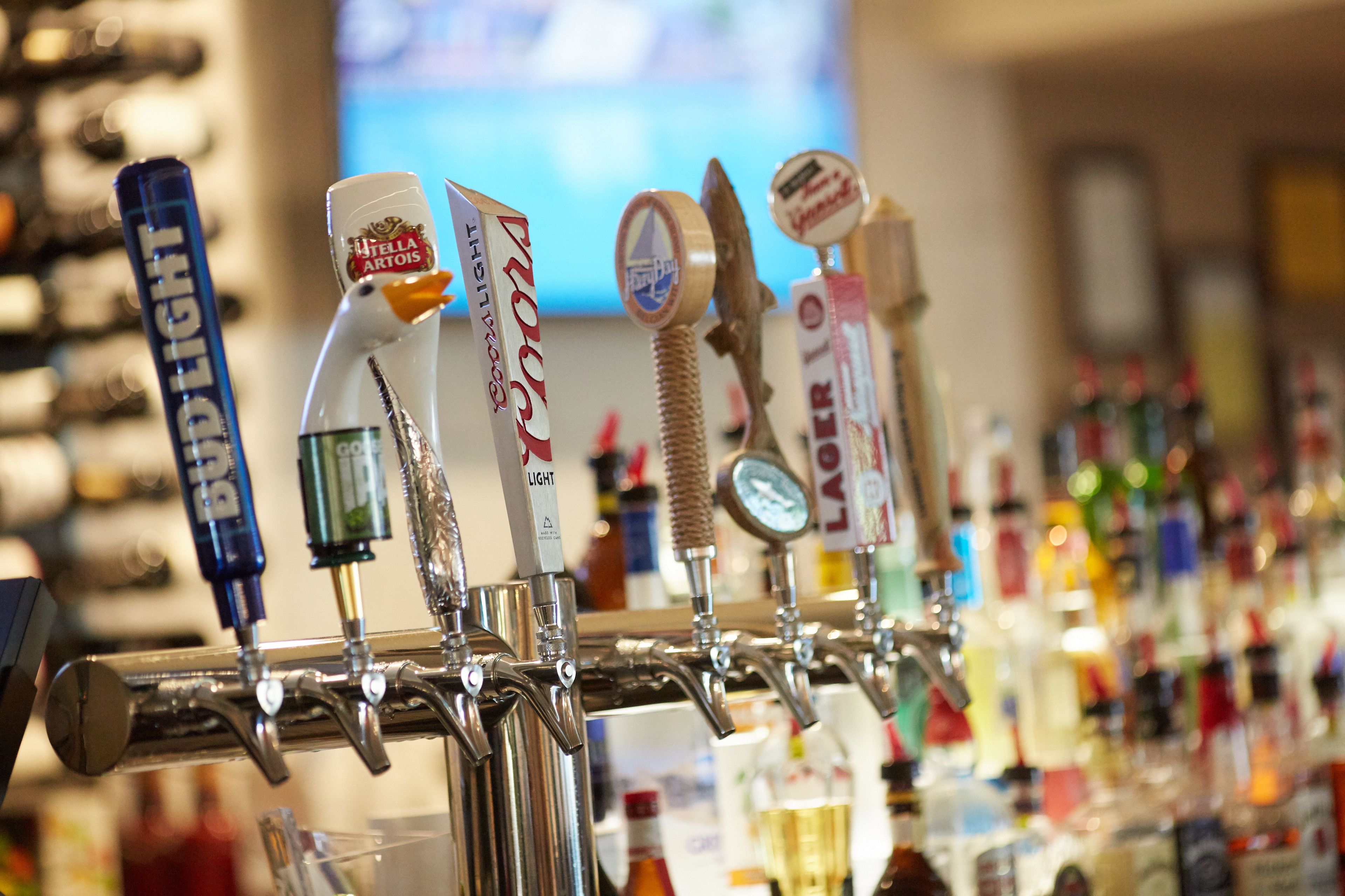 Un bar con varias griferías de cerveza y una variedad de botellas al fondo.