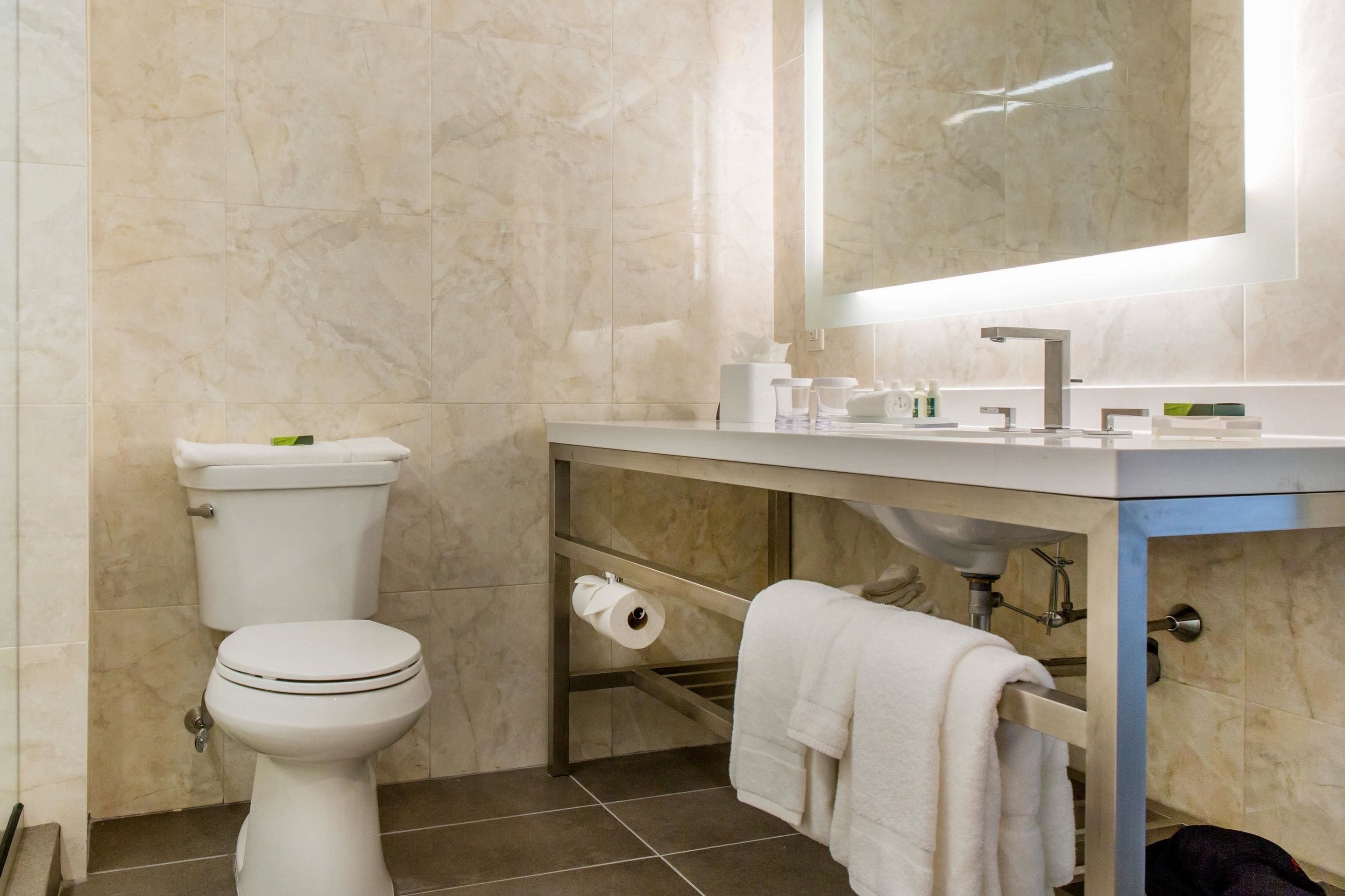 A modern bathroom with a toilet, sink, and mirror.