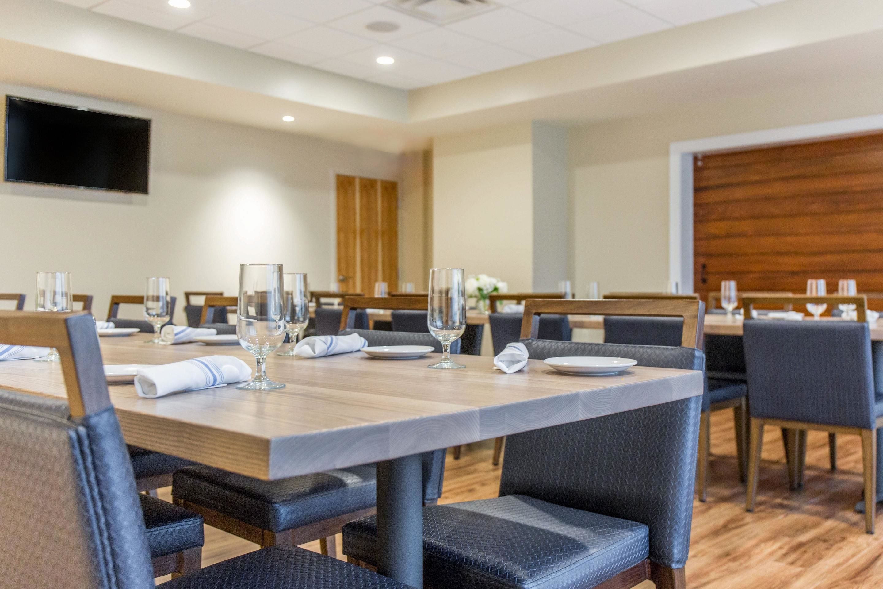 A conference room with a long table, chairs, and a flat-screen TV on the wall.
