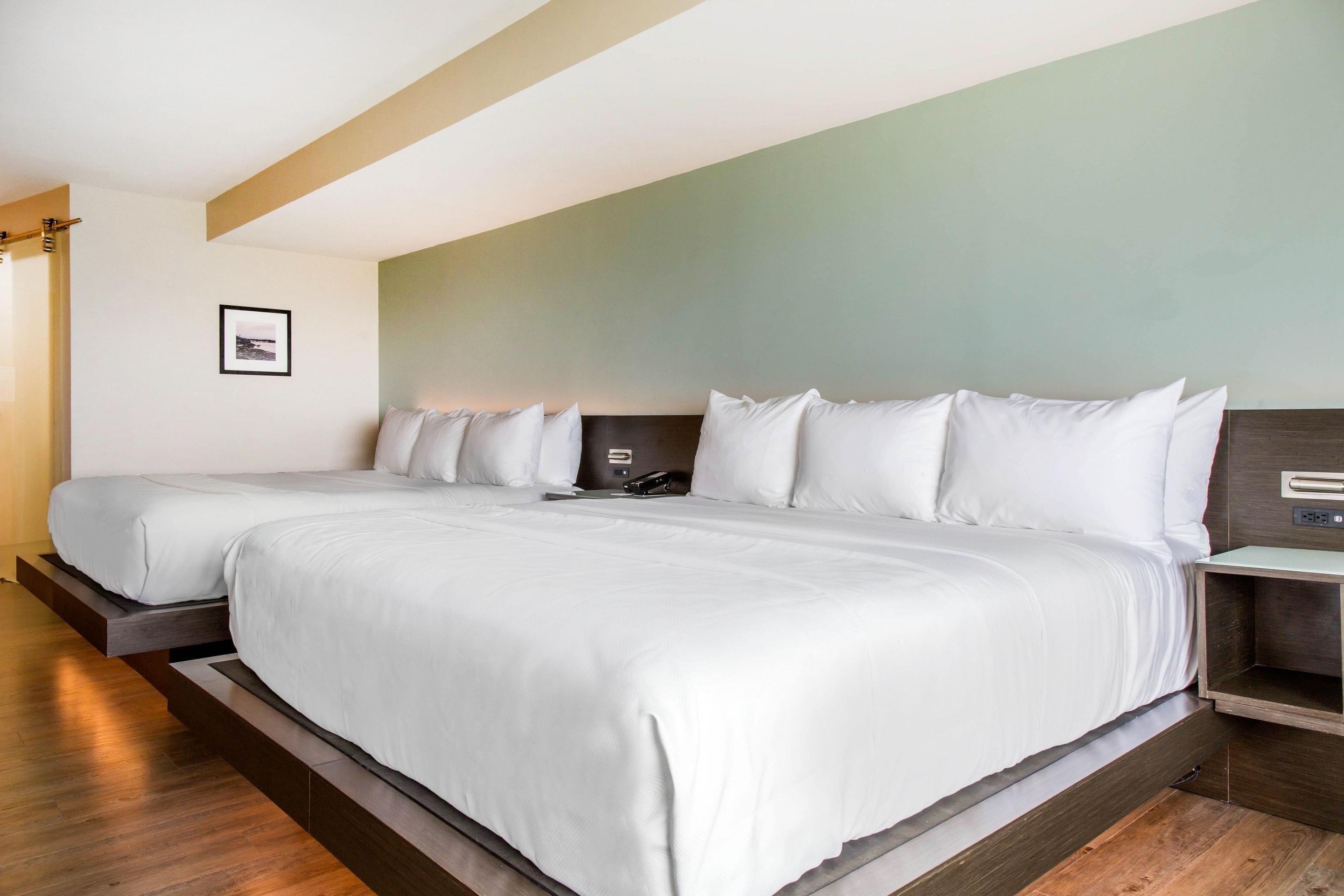 Una habitación de hotel moderna con una cama grande, una mesita de noche y un teléfono en la pared.