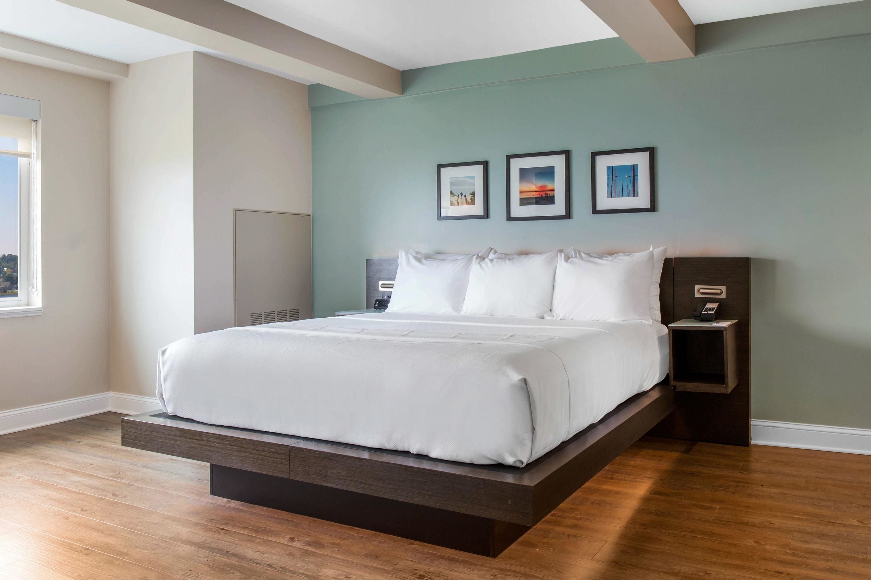 A modern bedroom with a platform bed, a nightstand, and a wall-mounted alarm clock.