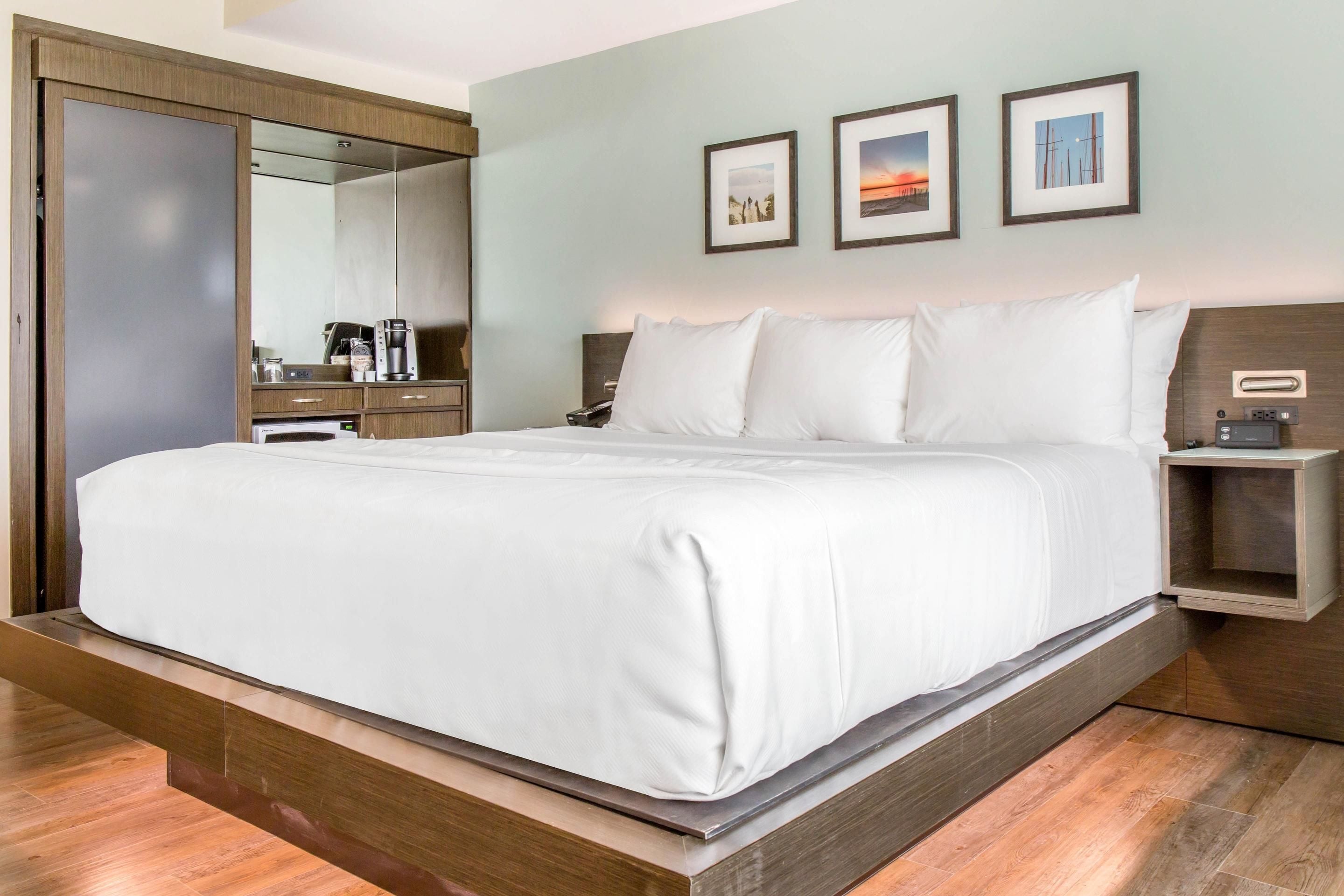 Une chambre d’hôtel moderne équipée d’un grand lit, d’une armoire, d’une table de chevet et d’une petite table de nuit.