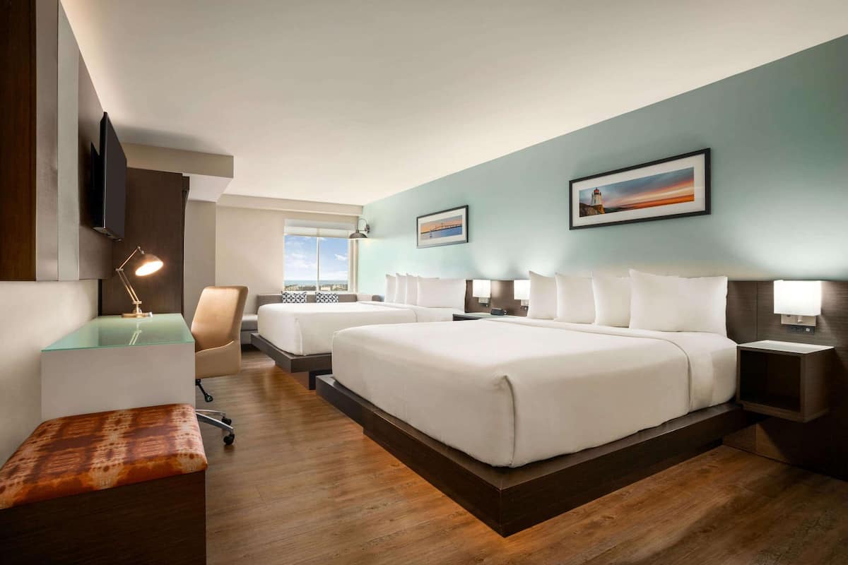 Une chambre d’hôtel avec deux lits, un bureau, une chaise et un banc.