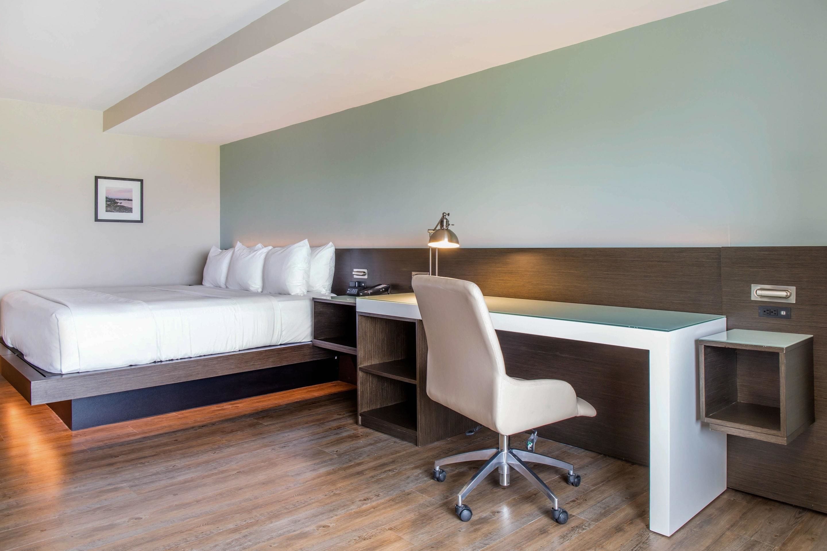 Een moderne hotelkamer met een bed, bureau en stoel.