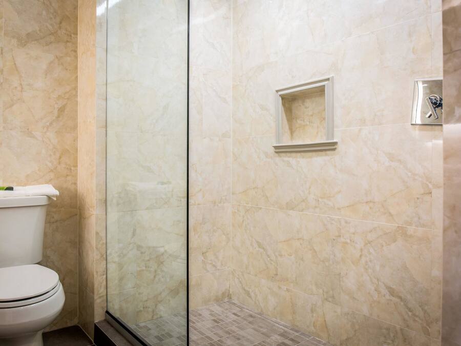 A bathroom with a toilet, a glass shower enclosure, and marble walls.