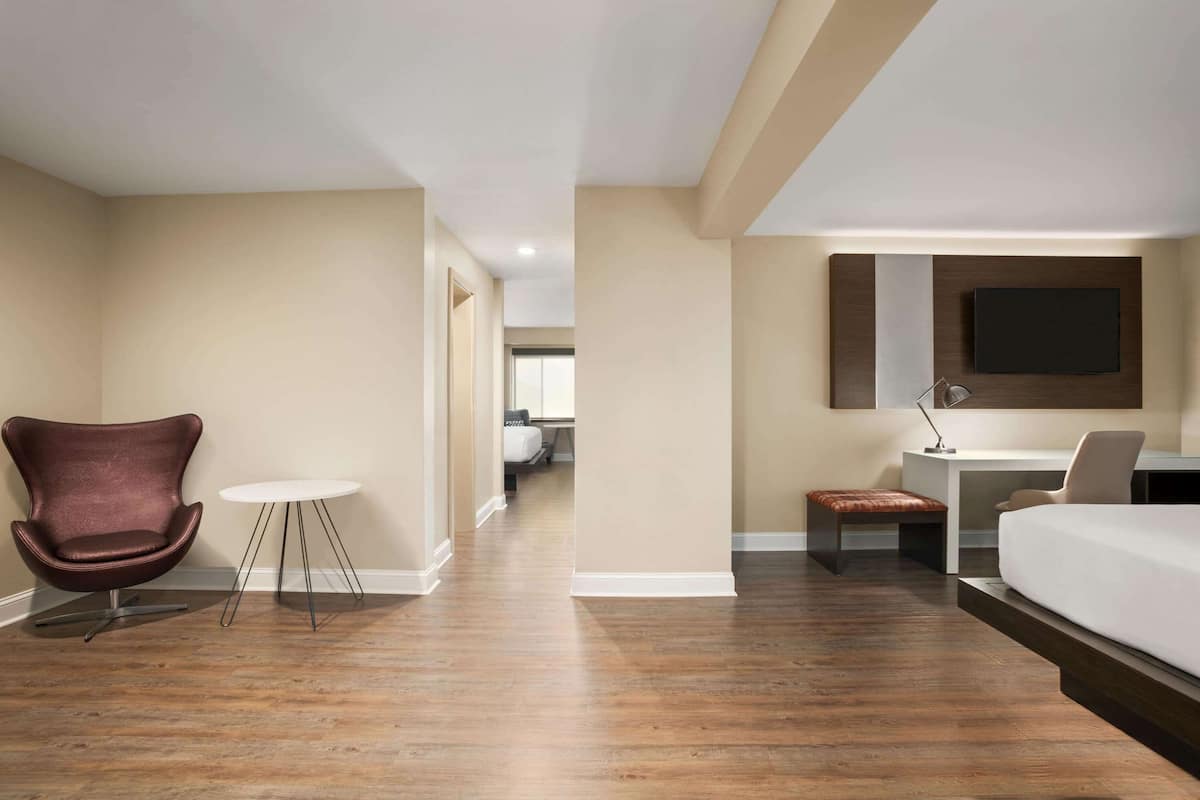 Une chambre d’hôtel équipée d’un lit, d’un bureau, d’une chaise, d’une petite table et d’un téléviseur fixé au mur.