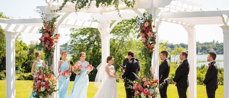 Una ceremonia de boda bajo un arco blanco con decoración floral.