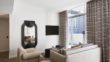 Une chambre d’hôtel moderne équipée d’un canapé, d’un fauteuil, d’une table ronde et d’un grand miroir.