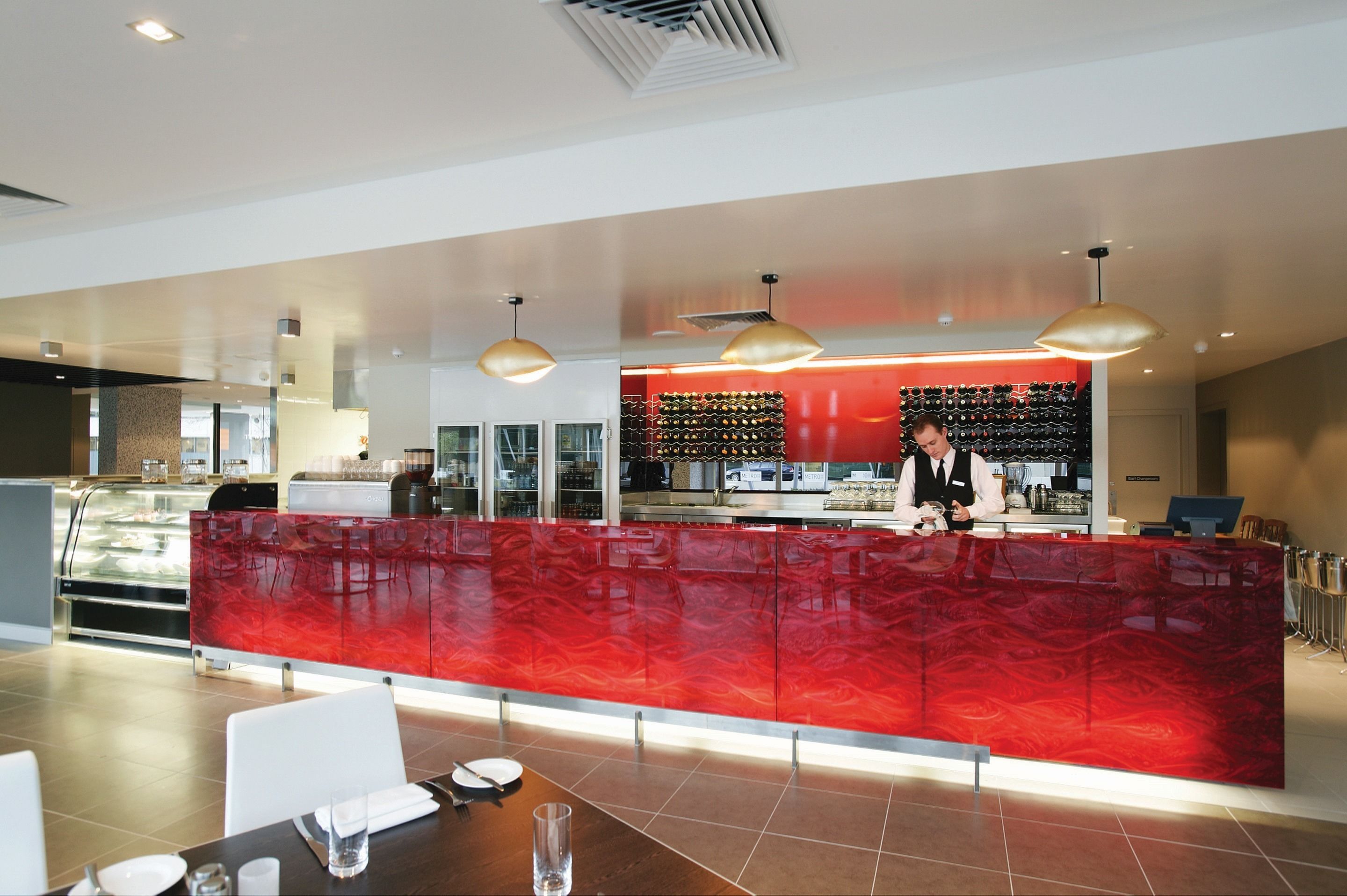 Un moderno vestíbulo de hotel con una recepción de mármol rojo, una bodega y una vitrina de cristal.
