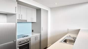 A modern kitchen with white cabinetry, a stainless steel sink, and a built-in oven.
