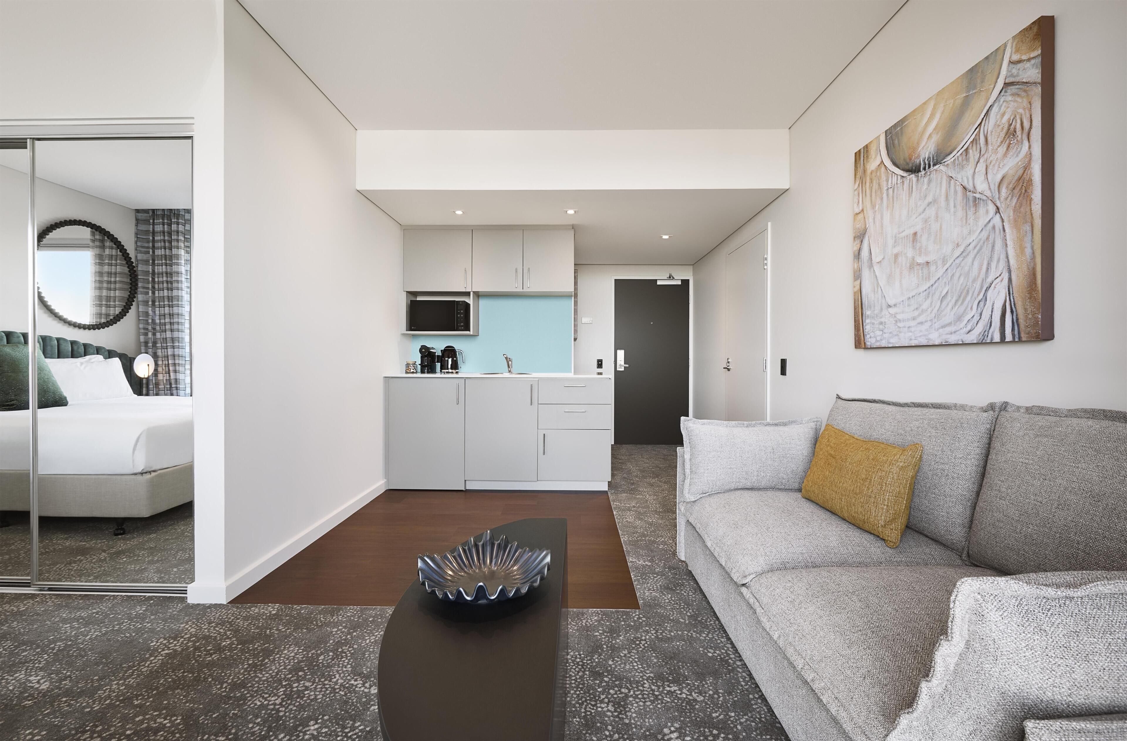 A modern living room with a grey sofa, a coffee table, and a painting on the wall.