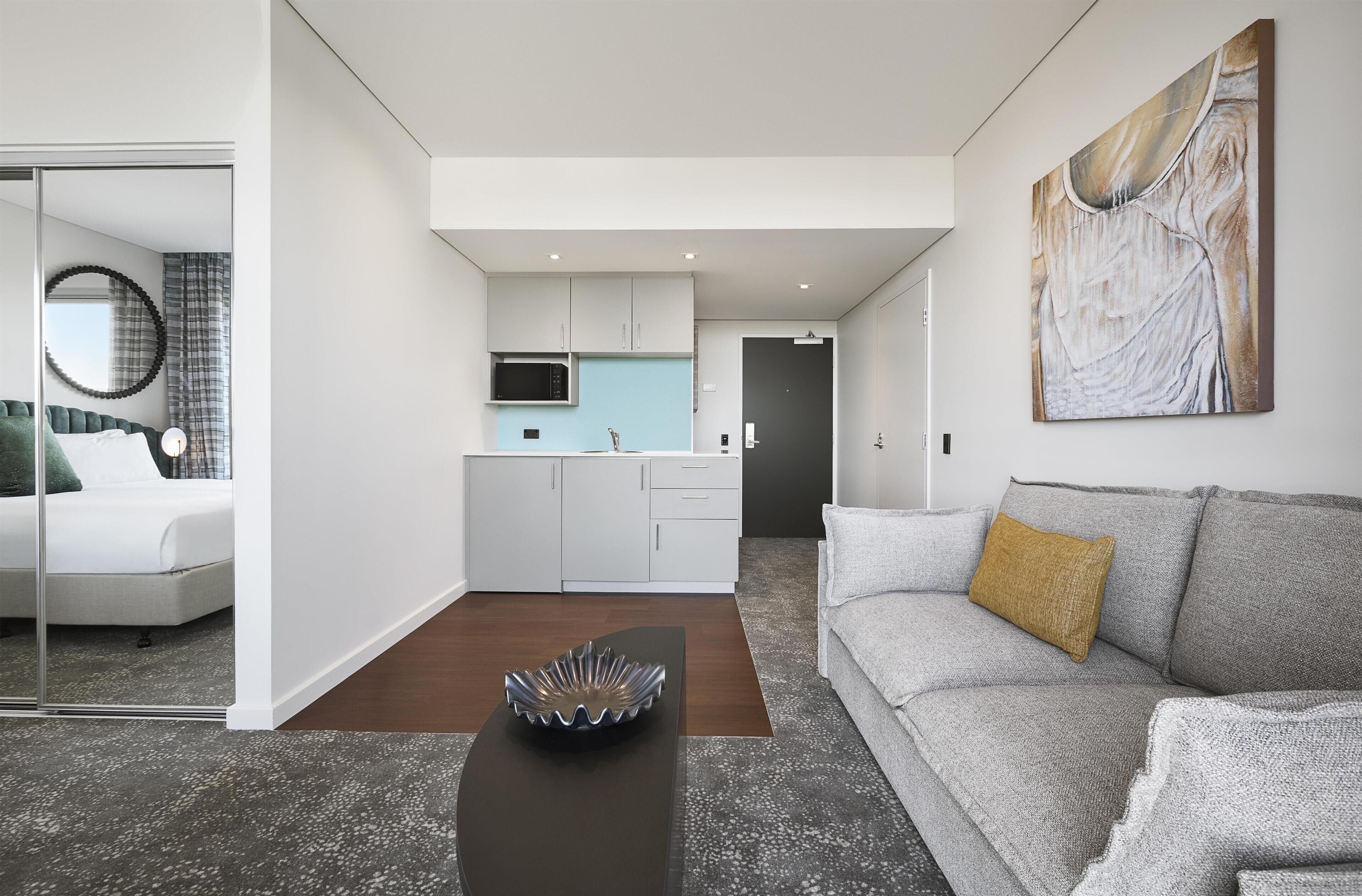 Un salon moderne avec un canapé gris, une table basse et un tableau accroché au mur.