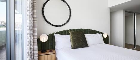 Ein modernes Hotelzimmer mit einem großen Bett, einer runden Wanddekoration, einem Nachttisch mit Lampe und Blick durch ein Fenster.