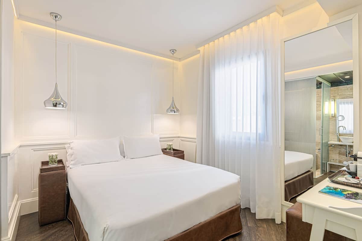 Een hotelkamer met een groot bed, nachtkastje, spiegel en douche.
