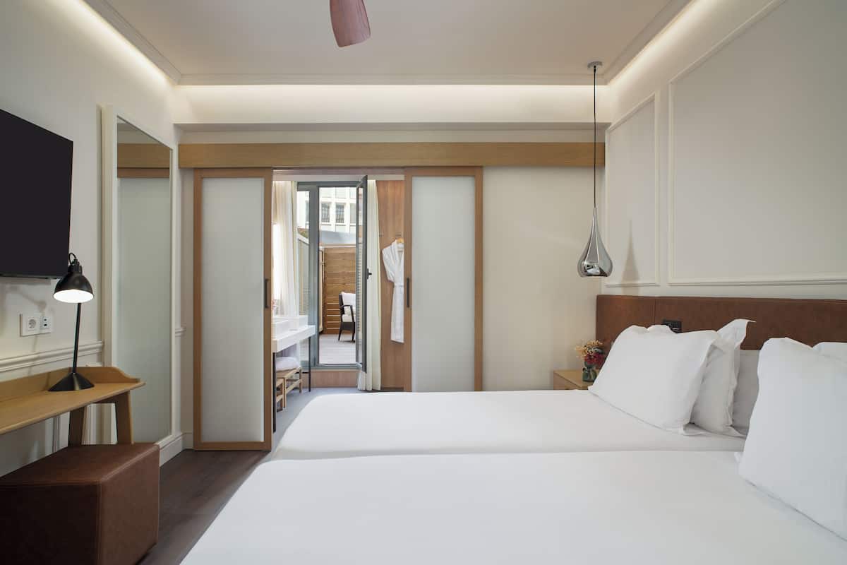 Een hotelkamer met een groot bed, nachtkastjes, een televisie en een badkamer zichtbaar door een geopende deur.