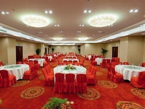 A banquet hall with round tables, red chairs, and a red carpet. - Oriental Deluxe (Hangzhou)