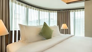 A hotel room with a large bed, two bedside lamps, and a view of the city through sheer curtains. - The Mirador Hotel, Mumbai International Airport (Mumbai)