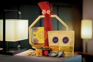 A table with a decorative gift box, two bags of snacks, and two jars of preserves.