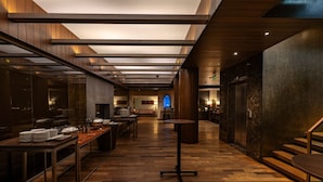A modern hotel lobby with a wooden floor, a central seating area, and a staircase leading to an upper level. - The Mirador Hotel, Mumbai International Airport (Mumbai)