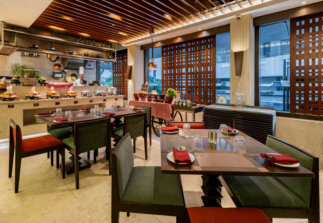 A restaurant with a modern interior, featuring wooden ceiling panels, large windows, and a view of the cityscape.